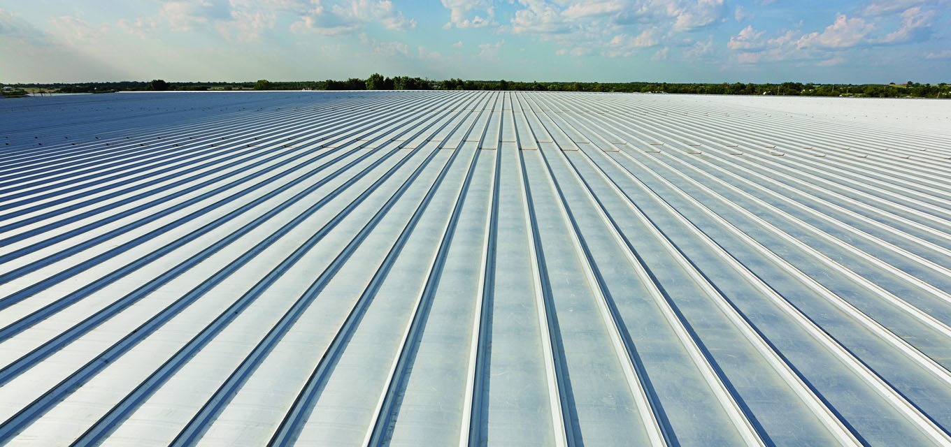 Large commercial building roof featuring a standing seam metal panel system with parallel seams stretching across the structure.